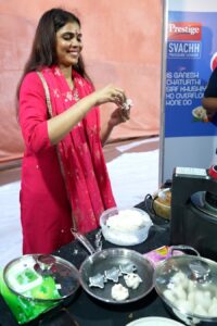 Visitors engage with TTK Prestige Svachh Shelter at Andhericha Raja during Ganesh Chaturthi 2025, taking selfies, participating in modak-making challenges, and pledging for clean kitchens and mindful water use